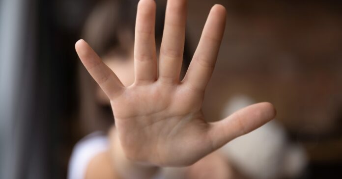 Adolescente usando celular en un aula, con pantalla reflejando alertas de redes sociales